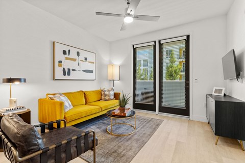 A living room with a yellow sofa and a black leather chair.