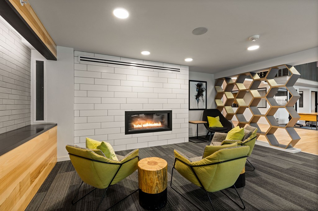 A modern living room with a fireplace and two green chairs.
