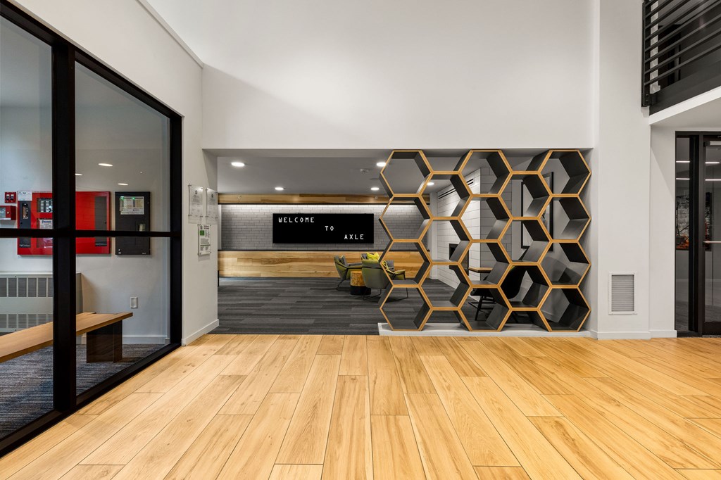 A hallway with a wooden floor and a wall with a hexagonal pattern.