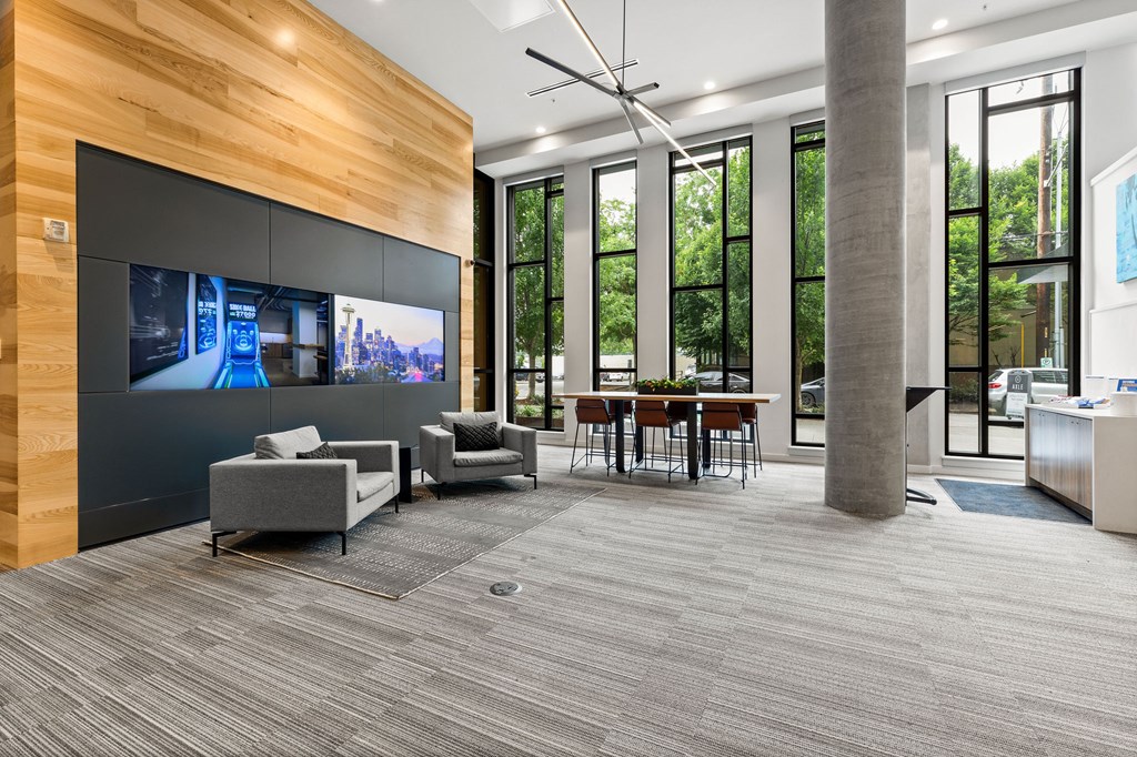 A modern waiting room with a TV on the wall and comfortable seating.