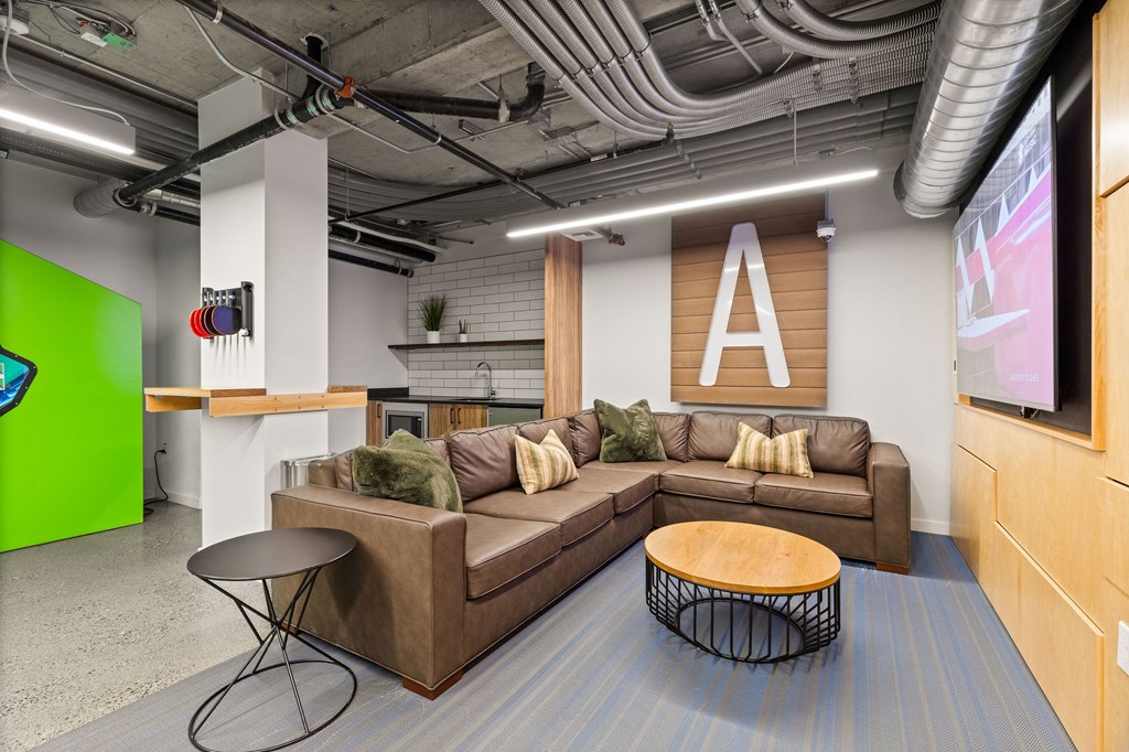 A modern office lounge with a brown sofa and a wooden coffee table.