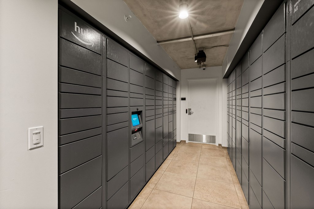A long hallway with a row of lockers on the side and a door at the end.