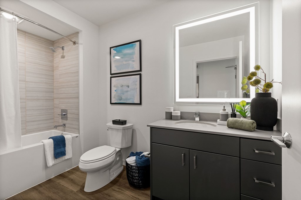 A bathroom with a white toilet, a white sink, and a white bathtub with a blue towel.