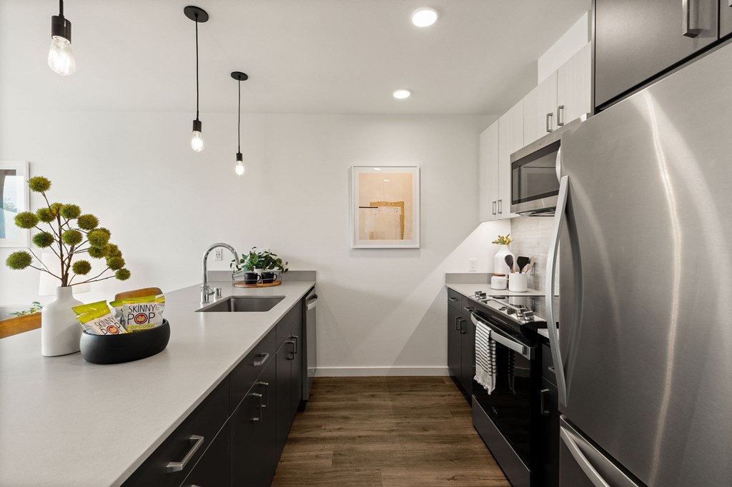 A modern kitchen with a stainless steel refrigerator and black cabinets.