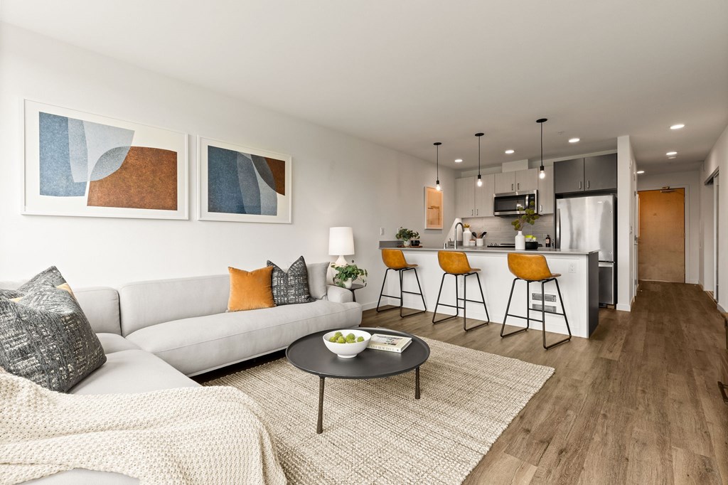 A modern living room with a grey sofa, a coffee table, and a bar area.