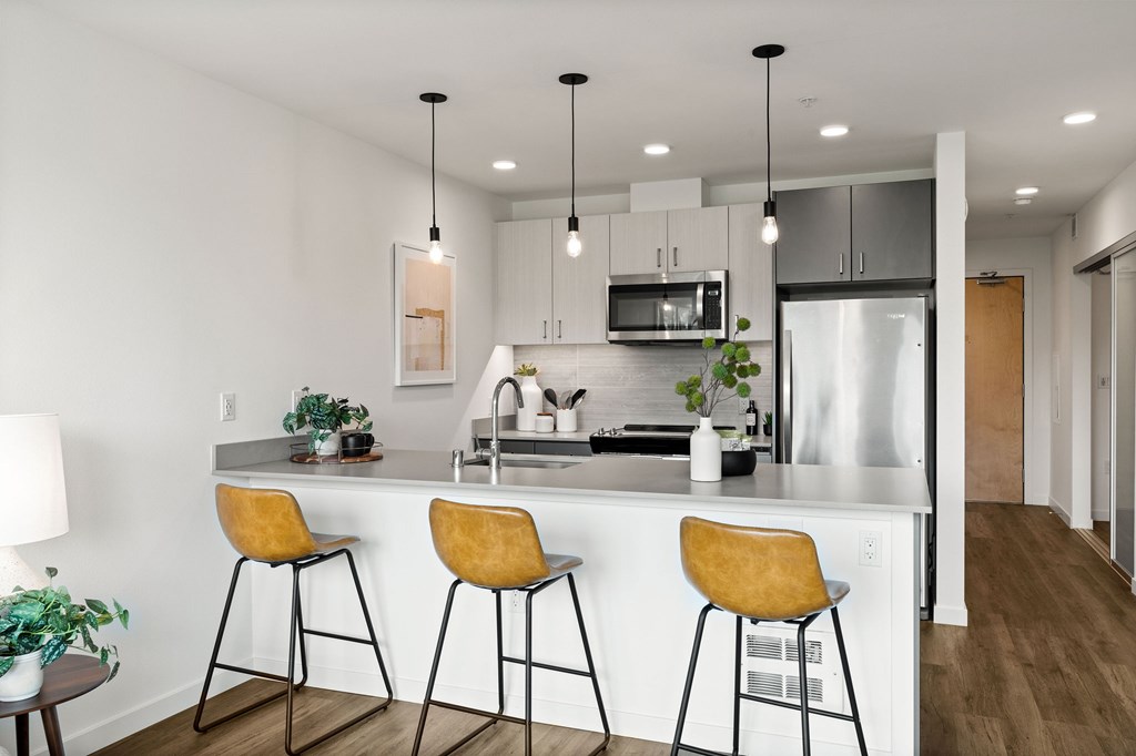 A kitchen with a white counter and yellow bar stools.
