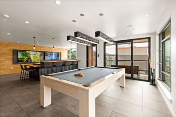 A pool table in a room with a bar and a television.