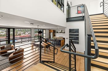 A staircase with a metal railing leads to a second floor with a balcony.