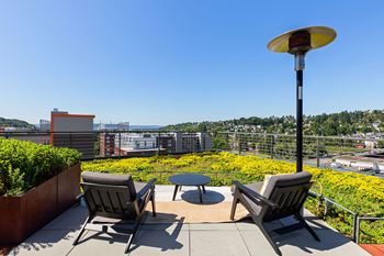 Two chairs and a table are on a patio overlooking a city.