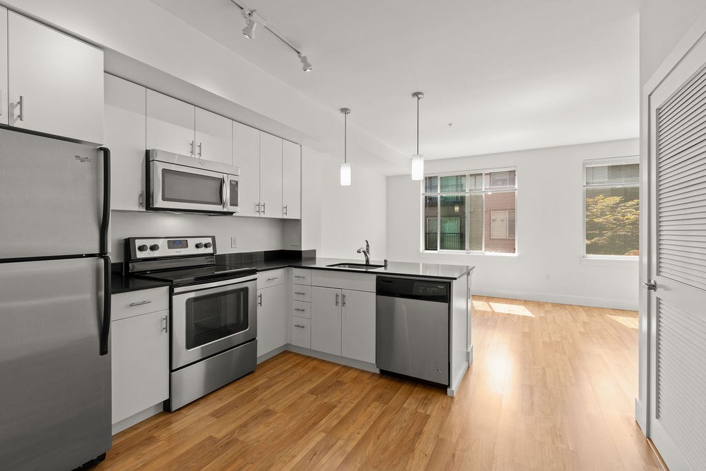 A modern kitchen with stainless steel appliances and wooden floors.