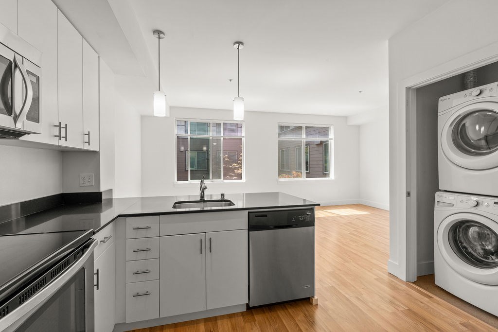 A modern kitchen with a black countertop and stainless steel appliances.