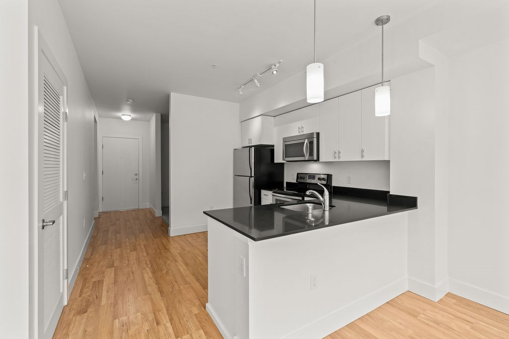 A kitchen with a black countertop and white cabinets.