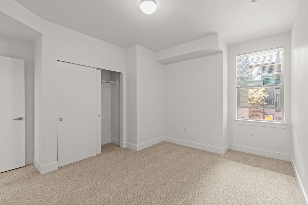 A room with a carpeted floor and a window showing a city view.