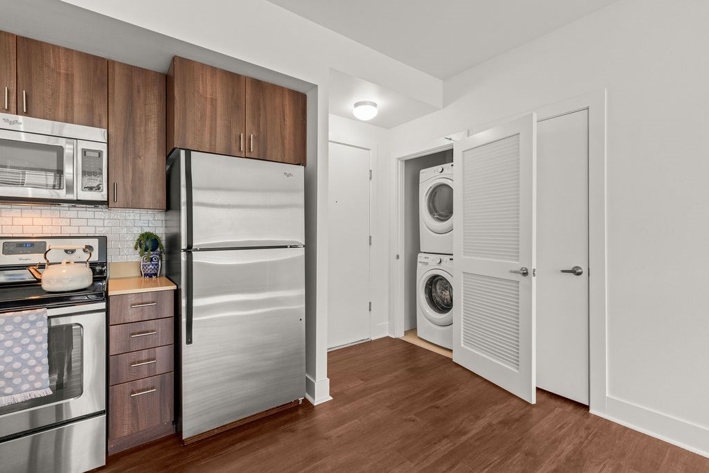 A kitchen with a refrigerator, oven, microwave, and a washing machine.