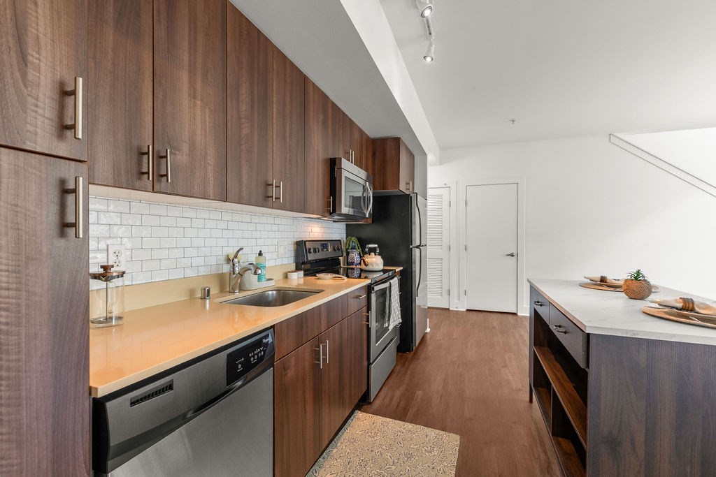 A modern kitchen with dark wood cabinets and stainless steel appliances.