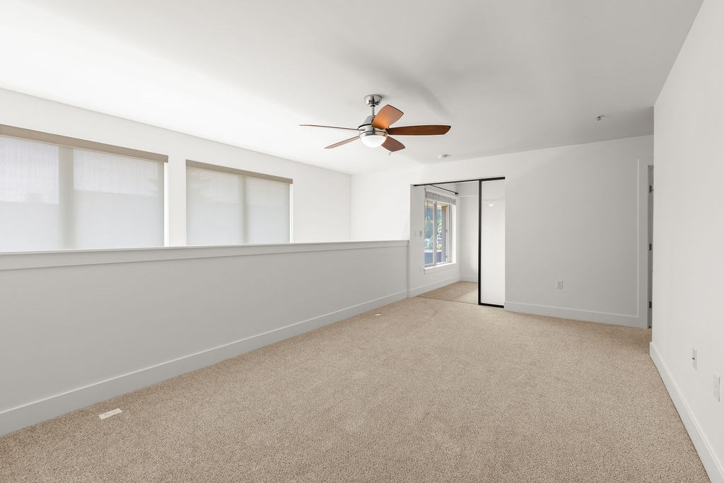 A room with a ceiling fan and carpeted floor.