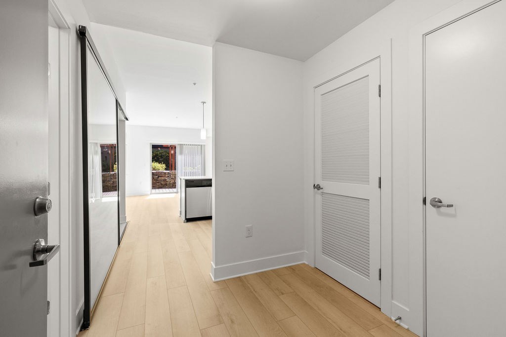 A hallway with white walls and wooden floors.