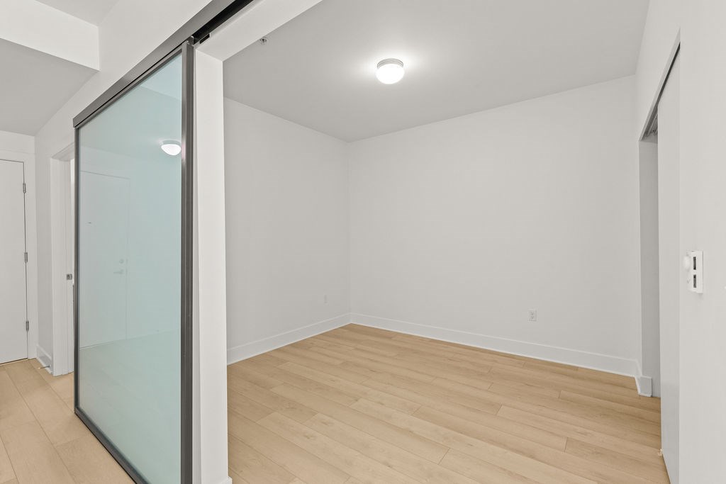 A room with a glass door and wooden flooring.