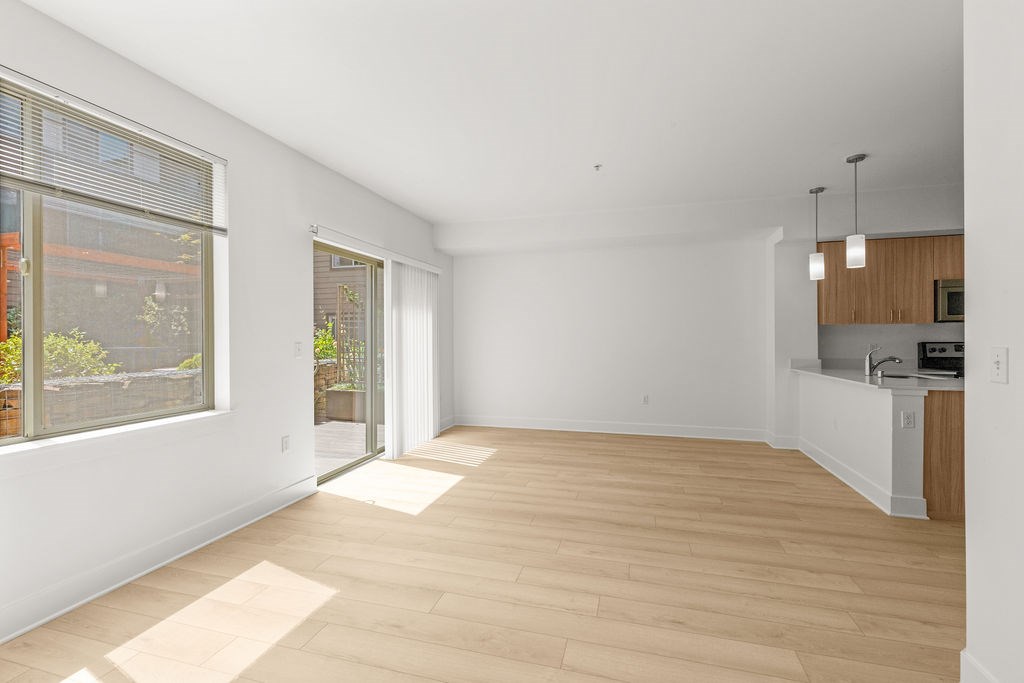 A spacious room with wooden flooring and white walls.