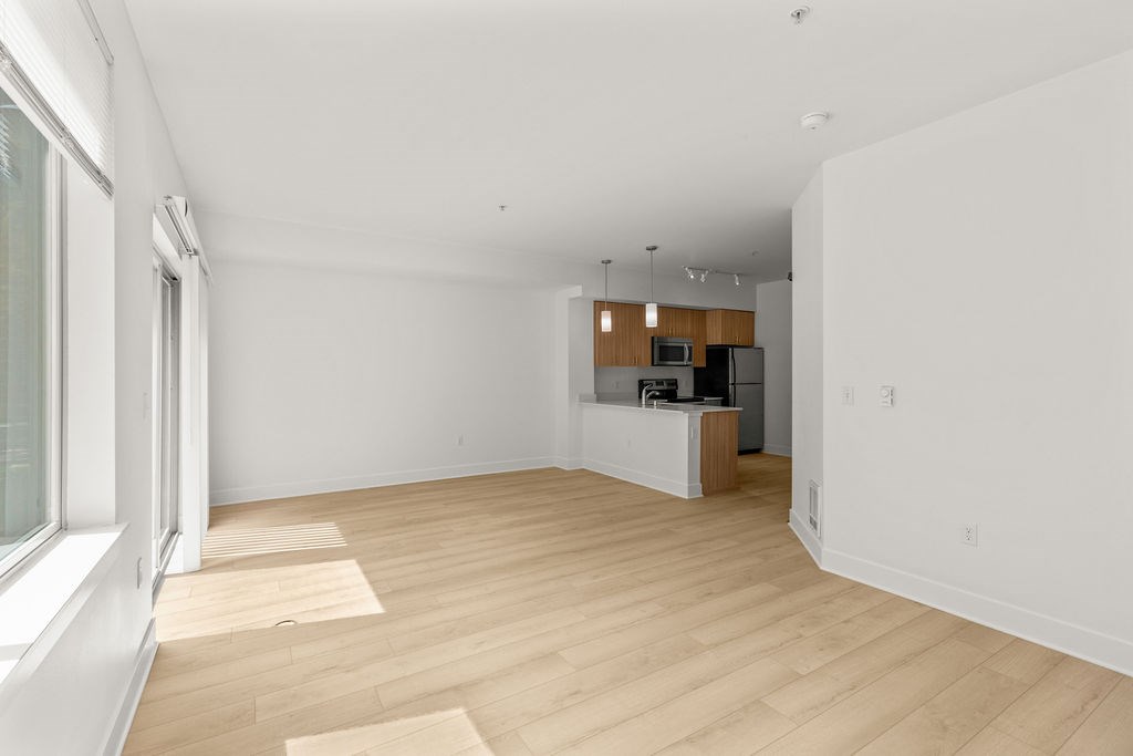 A spacious room with wooden flooring and a kitchenette in the corner.