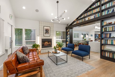 A living room with a brown leather couch, a coffee table, and a bookshelf filled with books.
