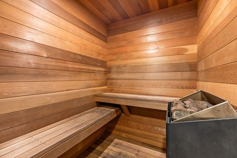 A wooden sauna with benches and a stone container.
