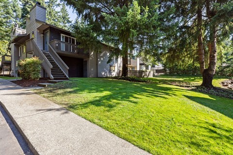A house with a balcony and a tree in front.