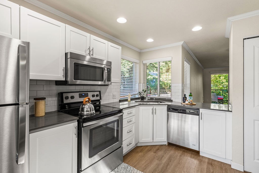 A modern kitchen with white cabinets and stainless steel appliances.