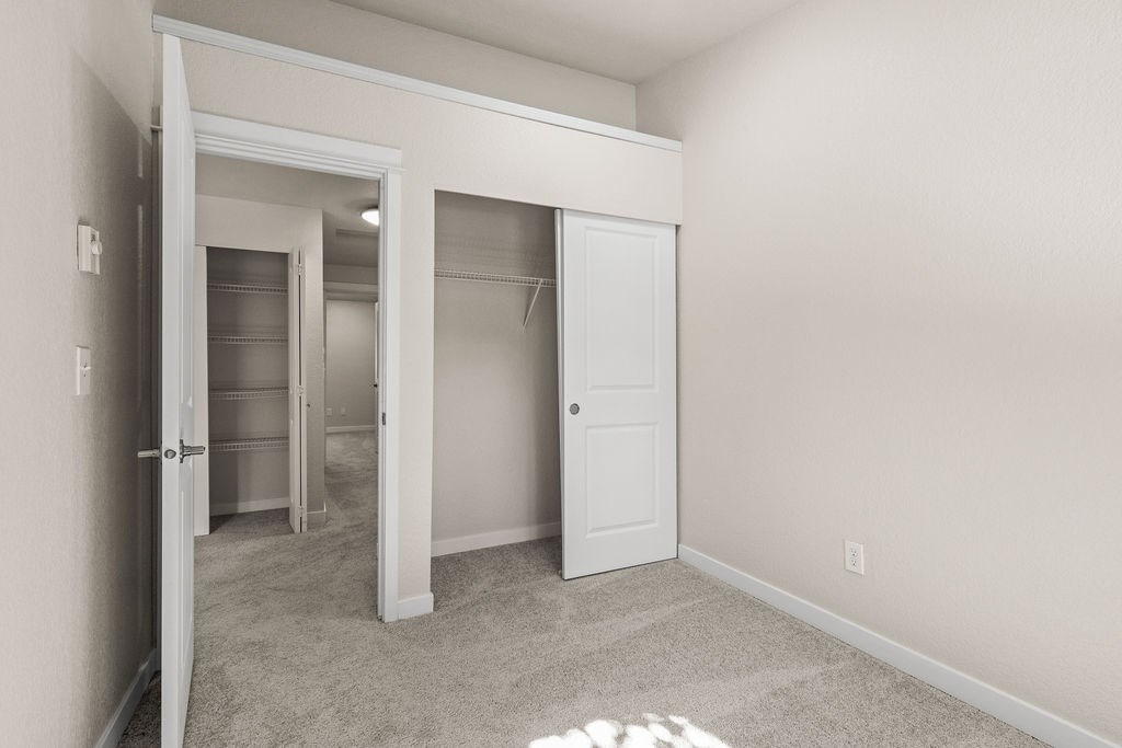A room with a white door and a carpeted floor.