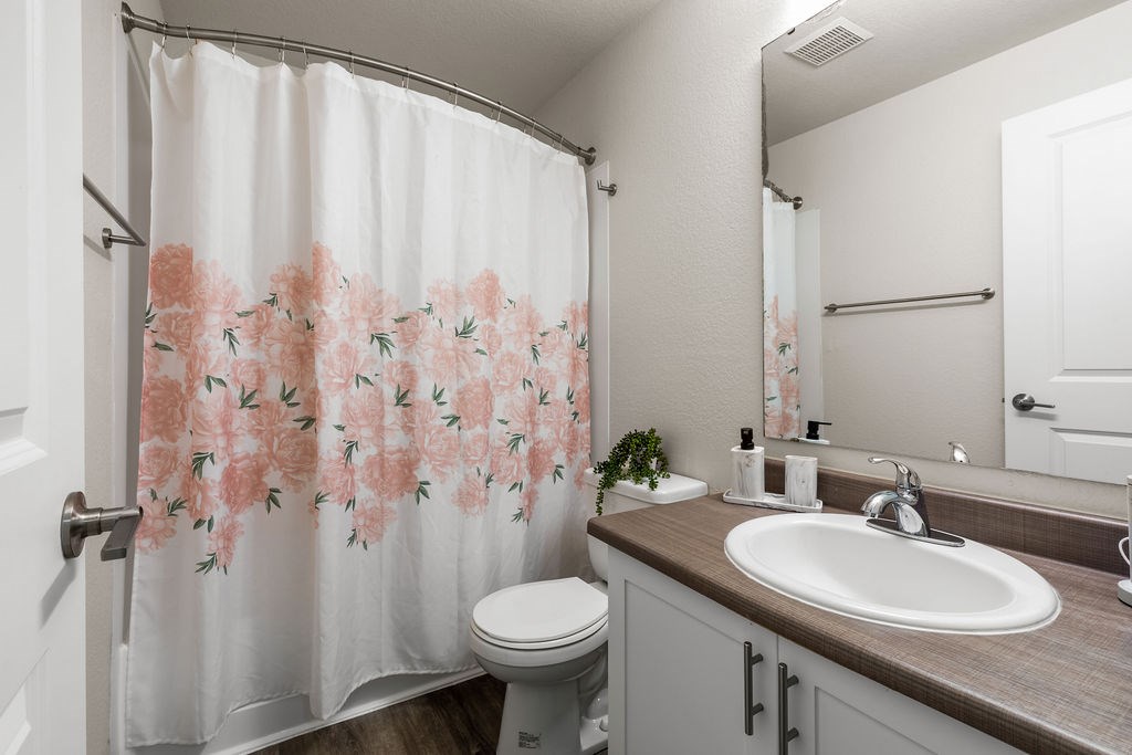 A bathroom with a floral shower curtain and a white toilet.