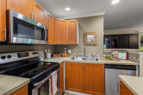 A kitchen with wooden cabinets and a stainless steel dishwasher.