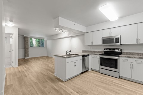A kitchen with white cabinets and a wooden floor.