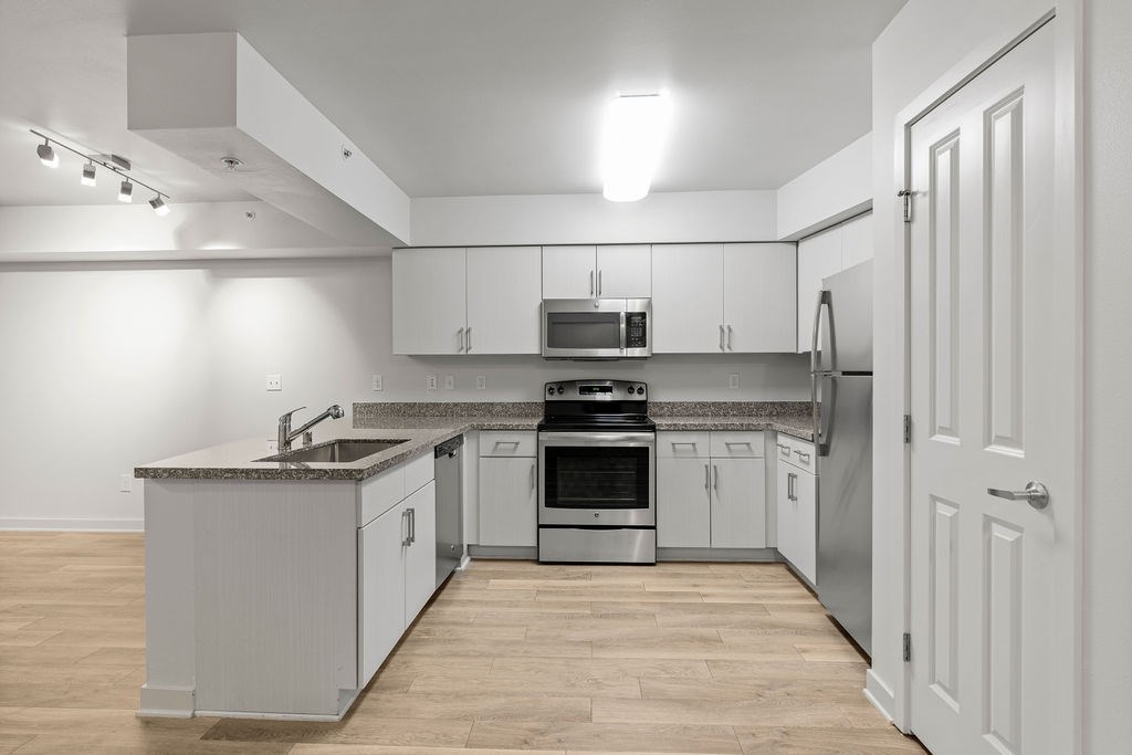 A kitchen with white cabinets and a wooden floor.