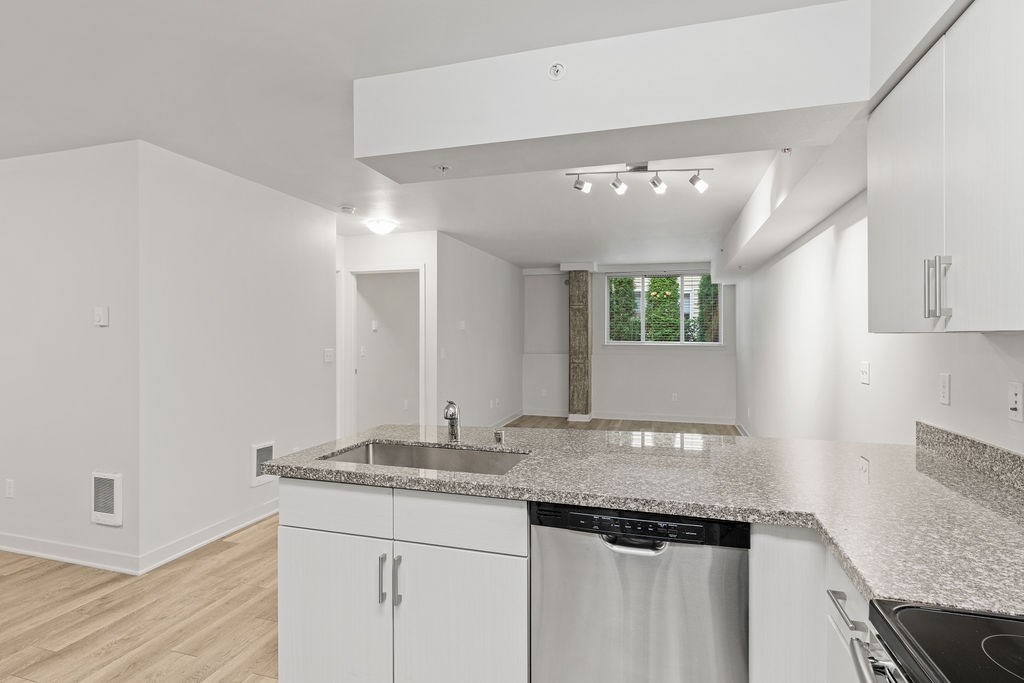 A kitchen with white cabinets and a granite countertop.