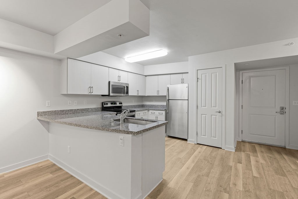 A kitchen with a granite countertop and white cabinets.