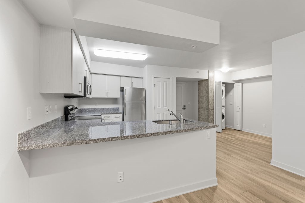 A kitchen with white cabinets and a granite countertop.