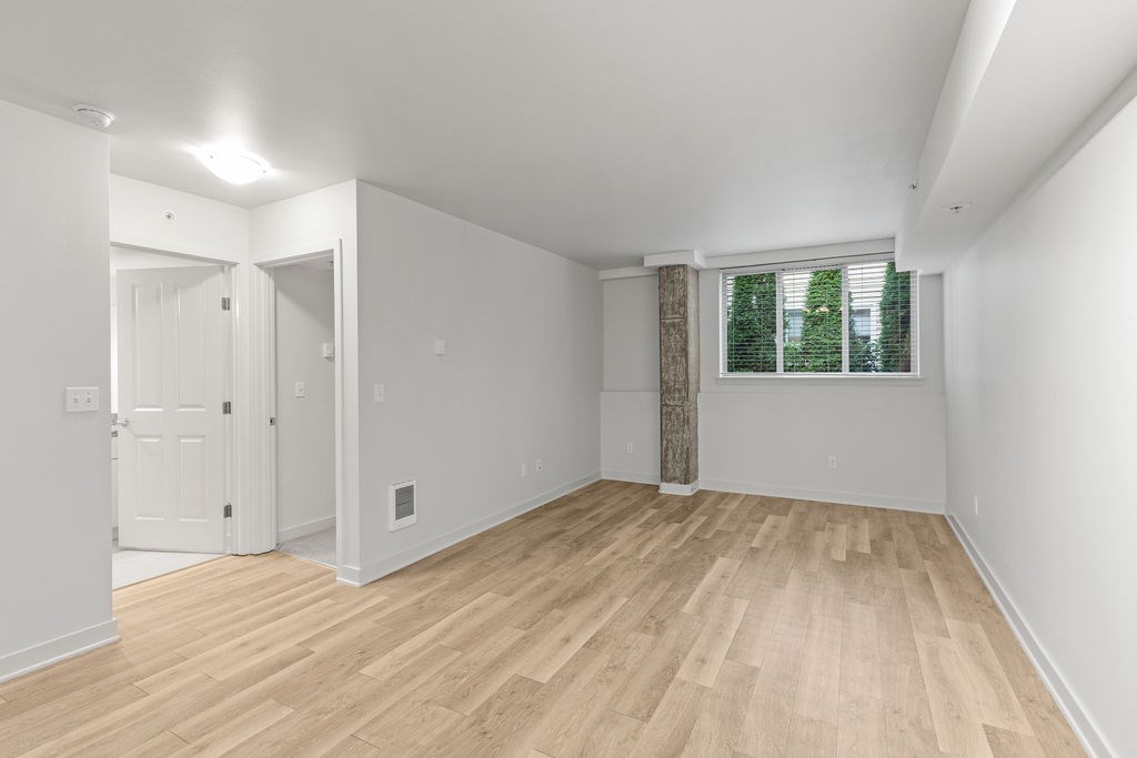 A room with wooden flooring and a window with blinds.