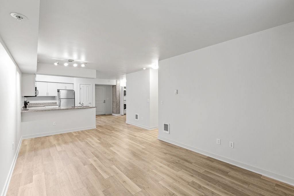 A spacious room with wooden flooring and white walls.