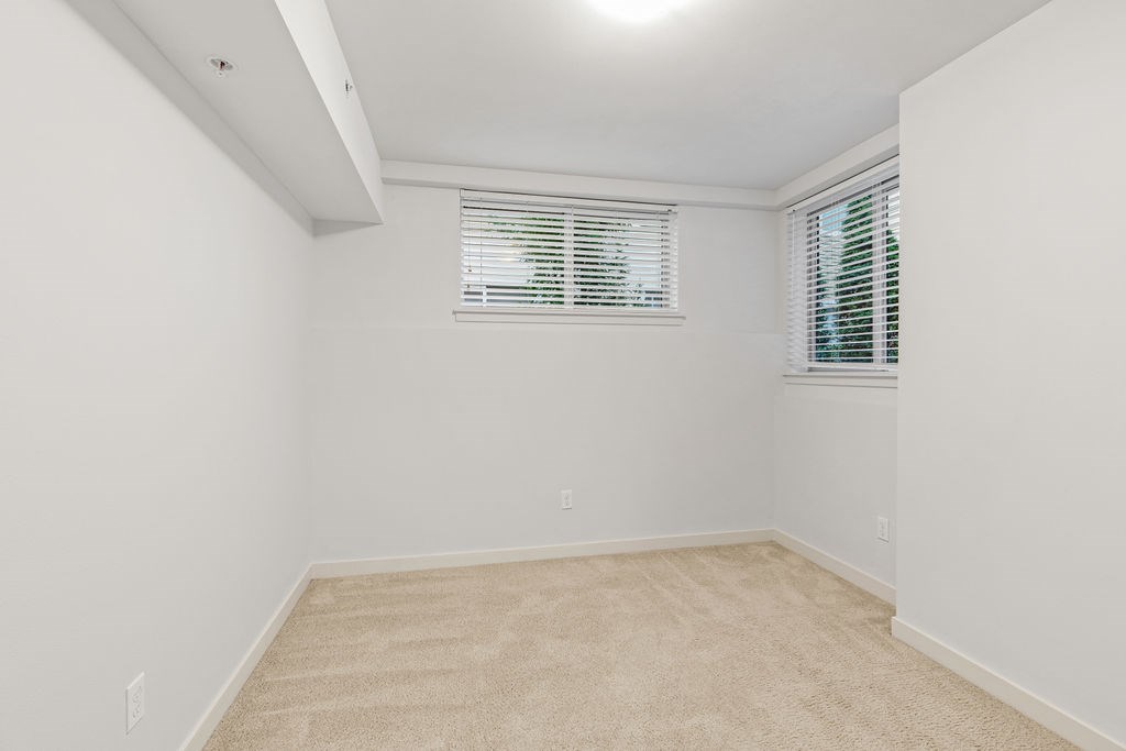 A room with a carpeted floor and a window with blinds.