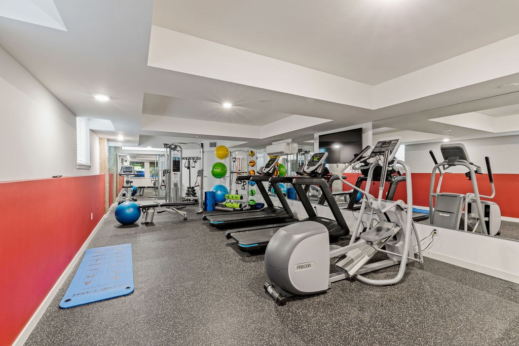 A gym with a variety of equipment including treadmills, exercise bikes, and weights.