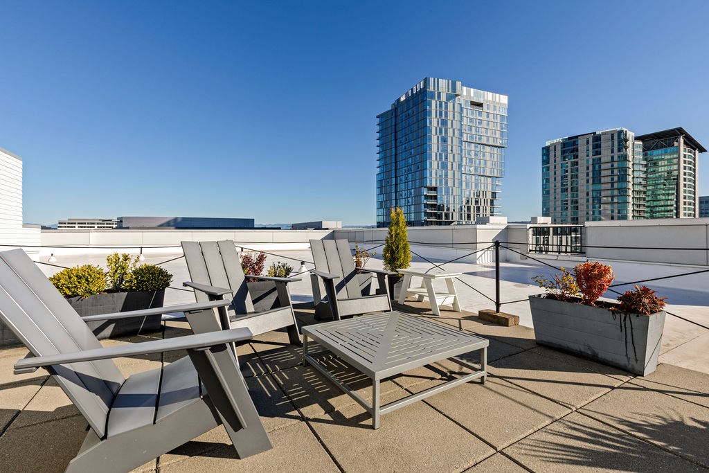 A patio with chairs and a table with a view of buildings in the background.