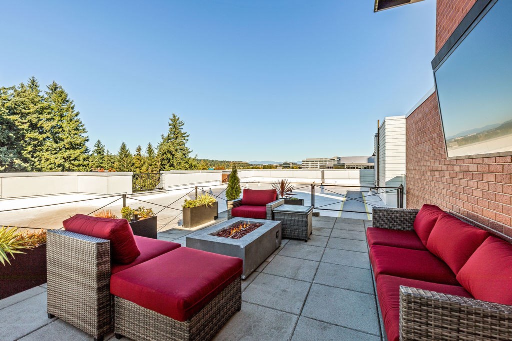 A patio with red cushions and grey wicker furniture.
