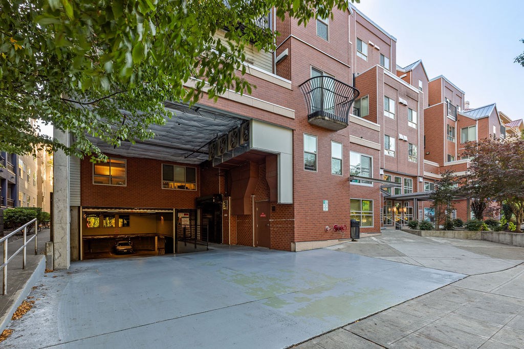 A red brick building with a black awning and a black metal basket hanging from it.