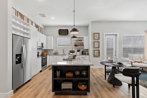 A modern kitchen with a refrigerator, oven, and a dining table with chairs.
