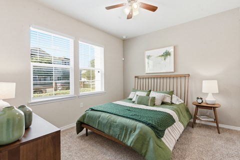A bedroom with a bed, nightstand, and window.