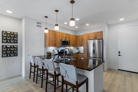 A modern kitchen with a black countertop and wooden cabinets.