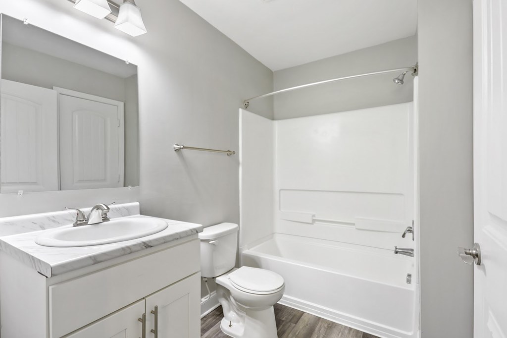 A white bathroom with a toilet, sink, and shower.