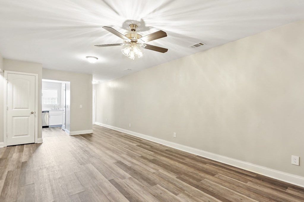 A room with a ceiling fan and wooden flooring.