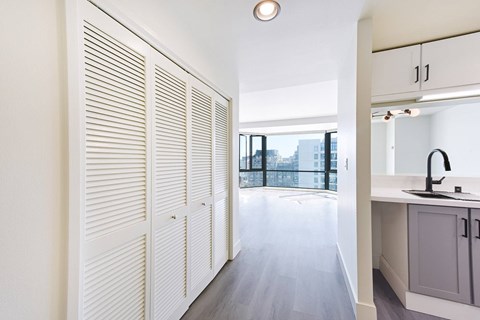 A kitchen with white cabinets and a window with blinds.