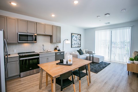 A kitchen with a table and chairs in the foreground and a couch in the background.